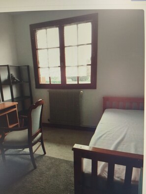A room with a bed, a desk, and a chair. There is a window with blinds. - Country Living: A Country House Furnished in a Traditional Style, Near a River and Forest (Malay-le-Grand)