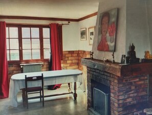 A room with a dining table, chairs, a radiator, a fireplace, and a Buddha statue. - Country Living: A Country House Furnished in a Traditional Style, Near a River and Forest (Malay-le-Grand)