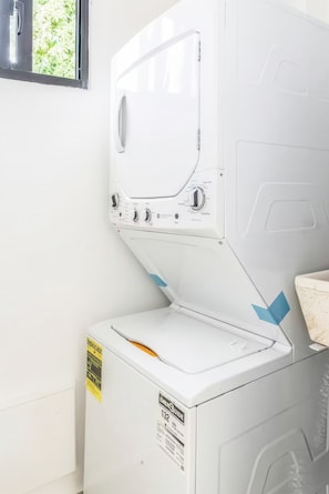 Une vue de face d’un lave-linge blanc, avec un panneau de commande, une étiquette indiquant son niveau d’efficacité énergétique et une fenêtre située au-dessus.