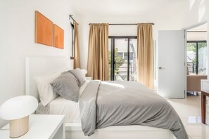 Ein modernes Schlafzimmer mit Bett, Nachttisch und Blick ins Freie durch große Fenster.