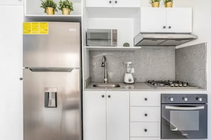 Une cuisine moderne dotée d’appareils électroménagers en acier inoxydable, d’un plan de travail en granit et de meubles blancs.