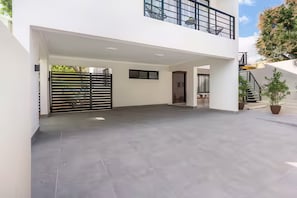 A spacious covered outdoor area with a modern design, featuring a flat roof and a black gate. - Nazar Suites - Entire 8-Bedroom Estate with Private Pool (Santiago de los Caballeros)