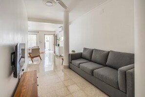 Ein modernes Wohnzimmer mit einem grauen Sofa, einem Holztisch und einem flachbildfernseher an der Wand.