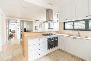 Een moderne keuken met een inbouwoven, een gasfornuis en een raam met zonwering.