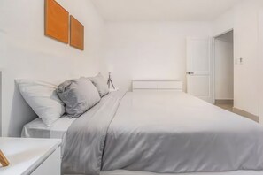 Ein modernes Schlafzimmer mit einem Bett, einem Nachttisch und einer Tür zu einem anderen Raum.