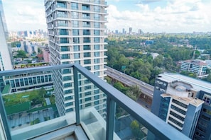 A high-rise building with multiple floors, large windows, and a view of a cityscape with other buildings and greenery. - Premium 1BR GTC Residence | Skyline Views (Nairobi)
