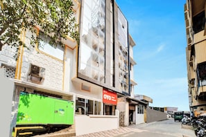 Un hotel con un cartel, una camioneta de mudanzas verde y una motocicleta estacionada.