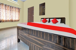 Un dormitorio con cama, puerta, ventana con cortinas y una obra de arte colgada en la pared.
