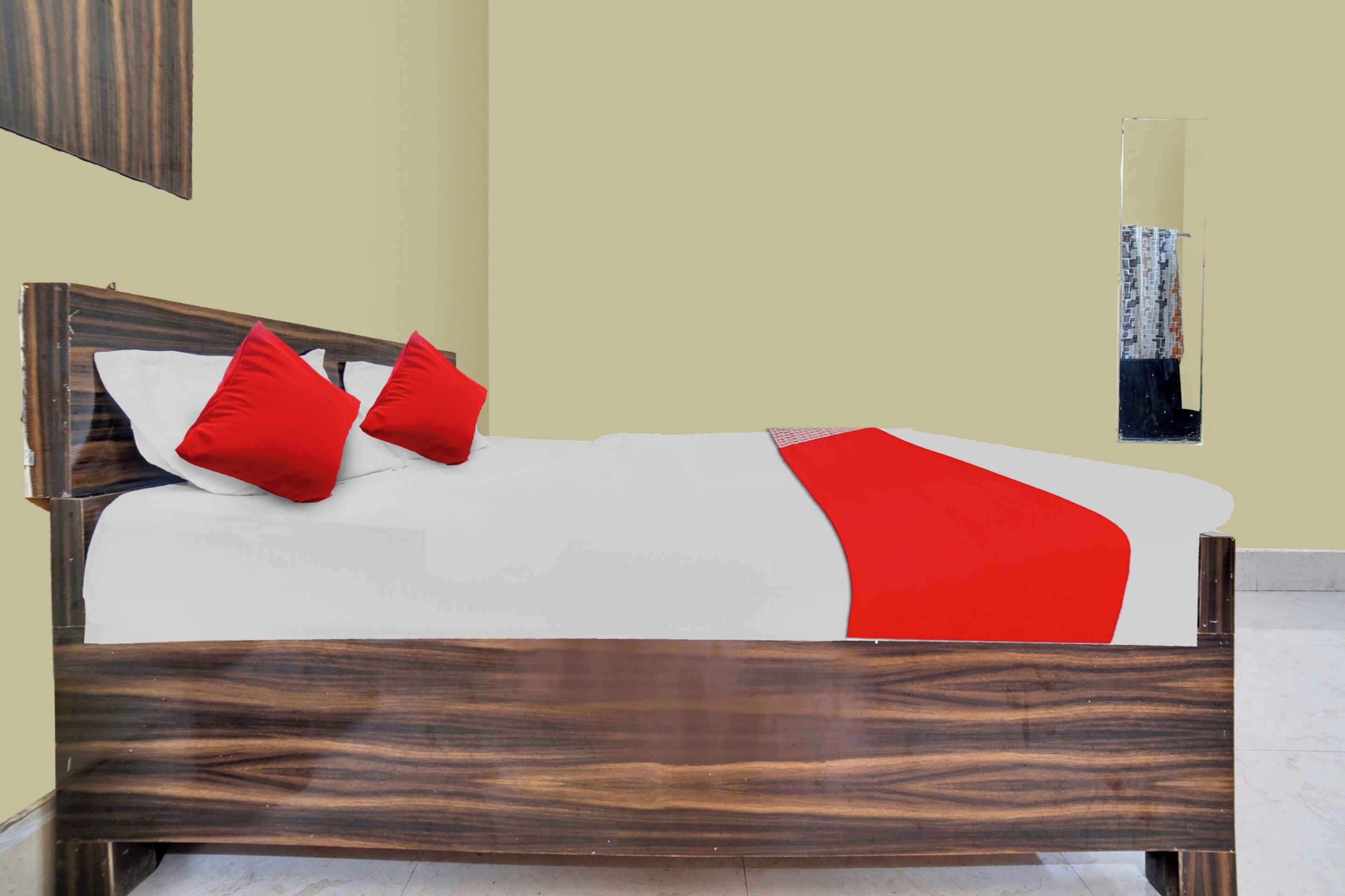 A bed with a wooden frame, white bedding, and red pillows.
