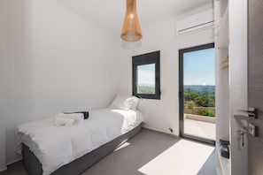 Ein Schlafzimmer mit Bett, Fenster und Blick ins Freie.