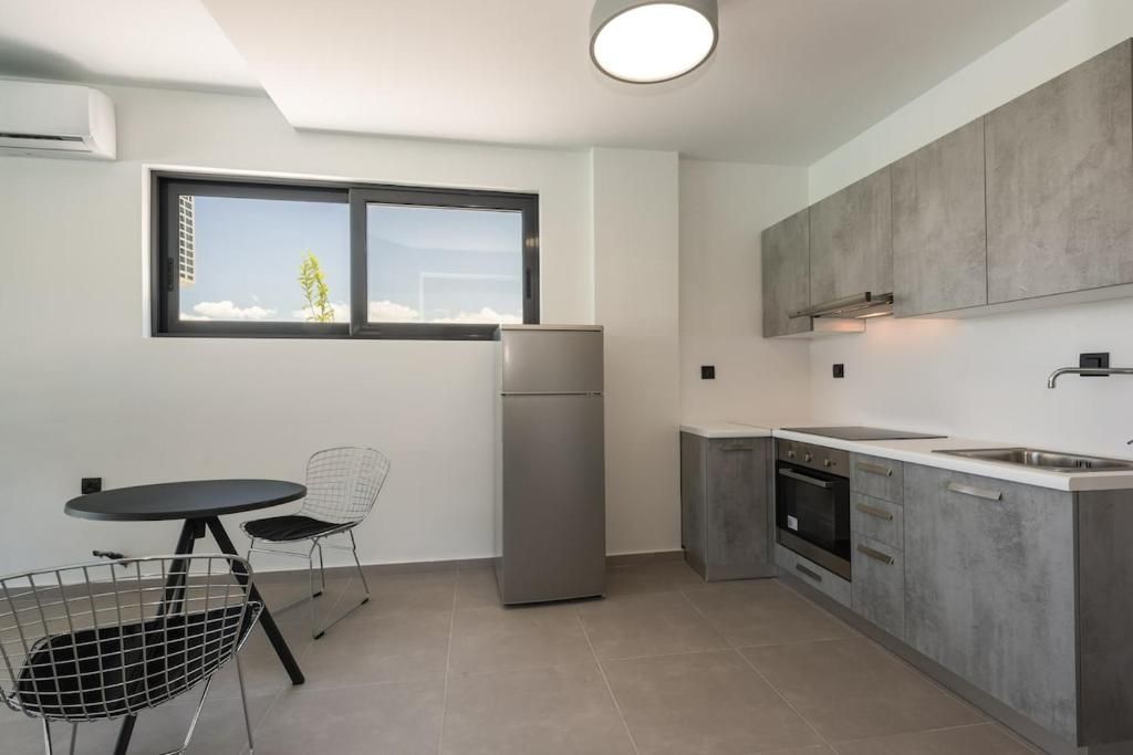 Eine moderne Küche mit Kühlschrank, Herd und Spüle, ein Essbereich mit Tisch und Stühlen sowie ein Fenster mit Blick.
