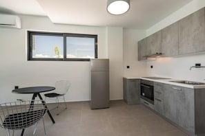 Eine moderne Küche mit Kühlschrank, Herd und Spüle, ein Essbereich mit Tisch und Stühlen sowie ein Fenster mit Blick.