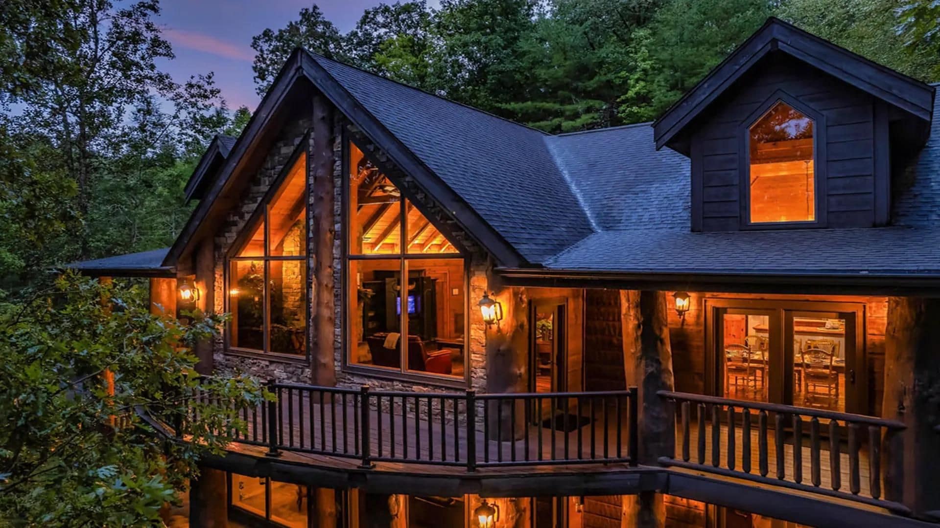 Une cabane en bois à deux étages, dotée d’un balcon, de grandes fenêtres et de fondations en pierre.