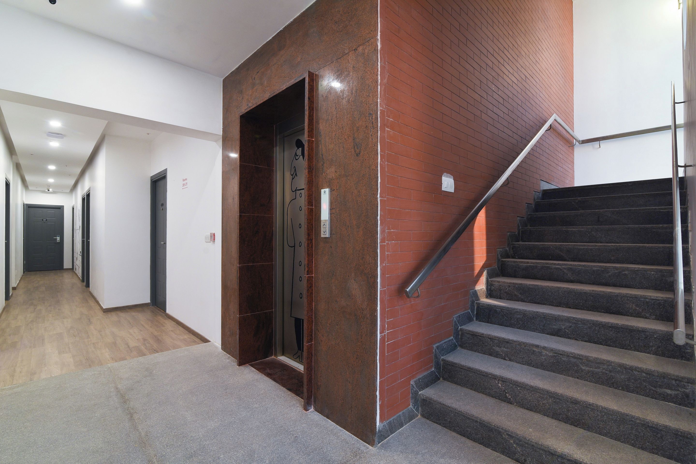 A hallway with a staircase leading to an elevator.