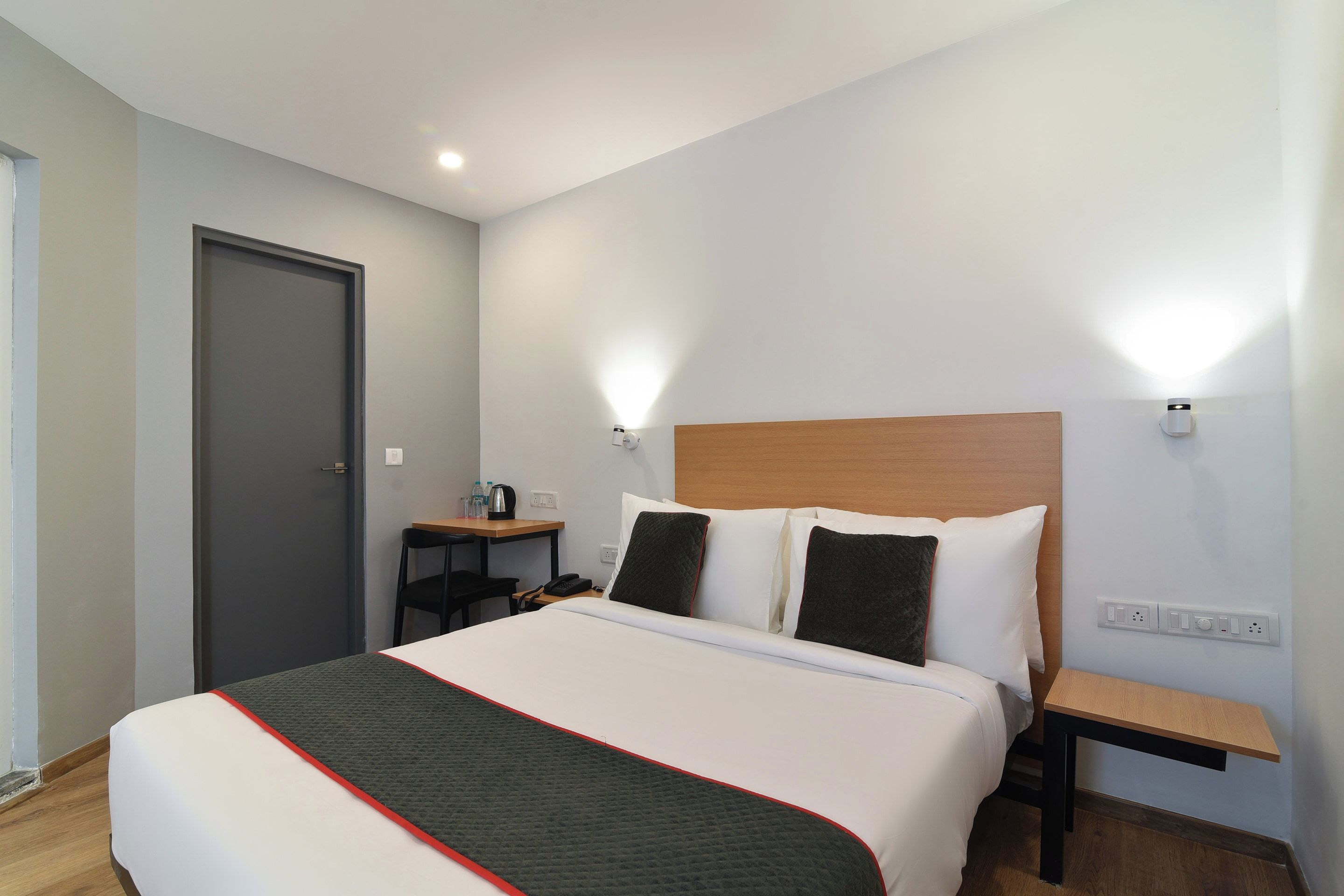 Una habitación de hotel con una cama, mesitas de noche, un escritorio y una silla.