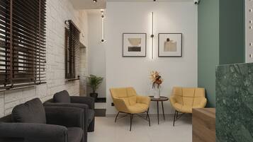 A modern waiting area with a stone wall, a potted plant, and two yellow chairs.