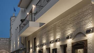 A two-story building with a stone facade, multiple balconies, and outdoor lighting.