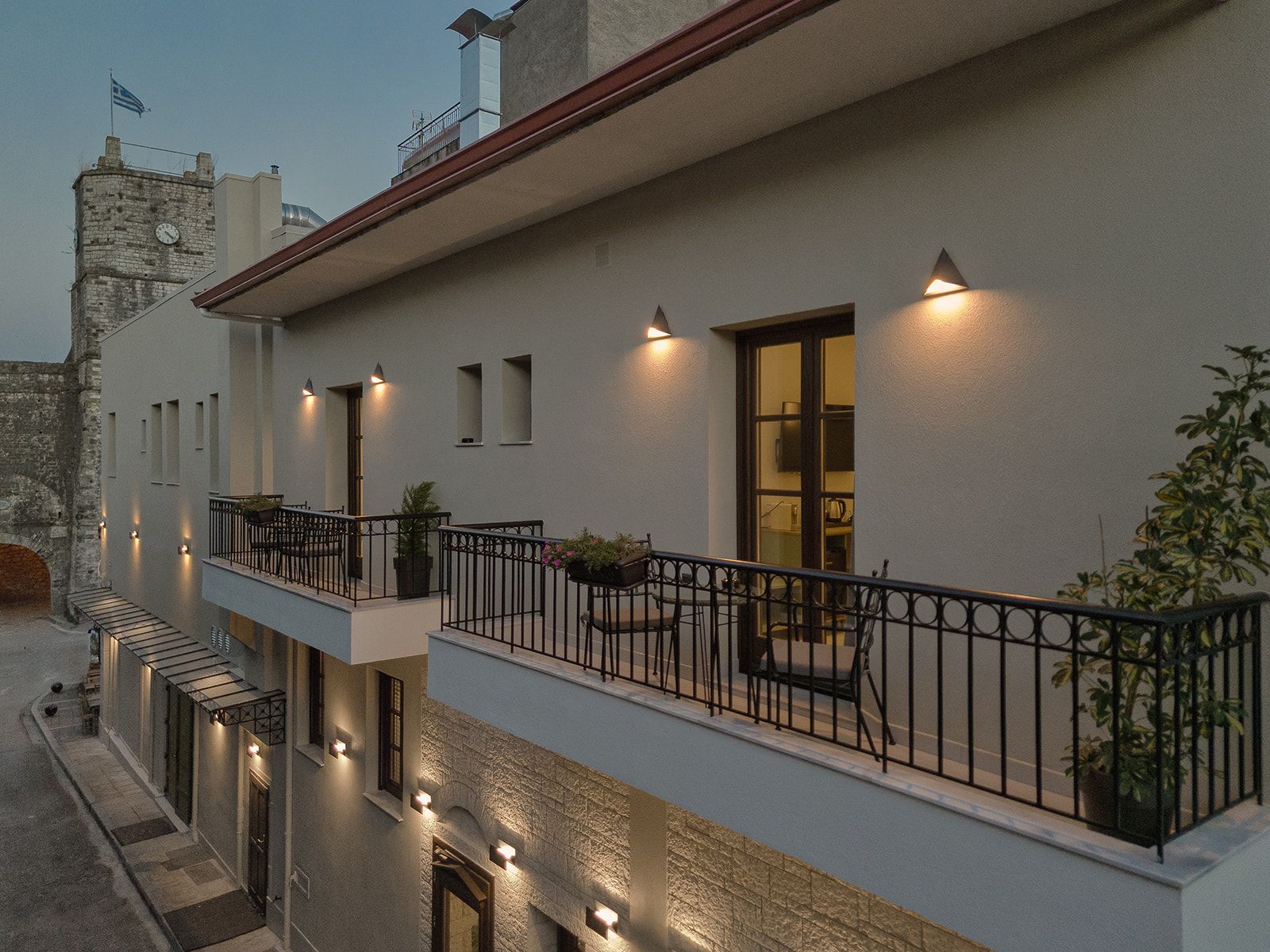 A multi-story building with a balcony, outdoor lighting, and a clock on the facade.