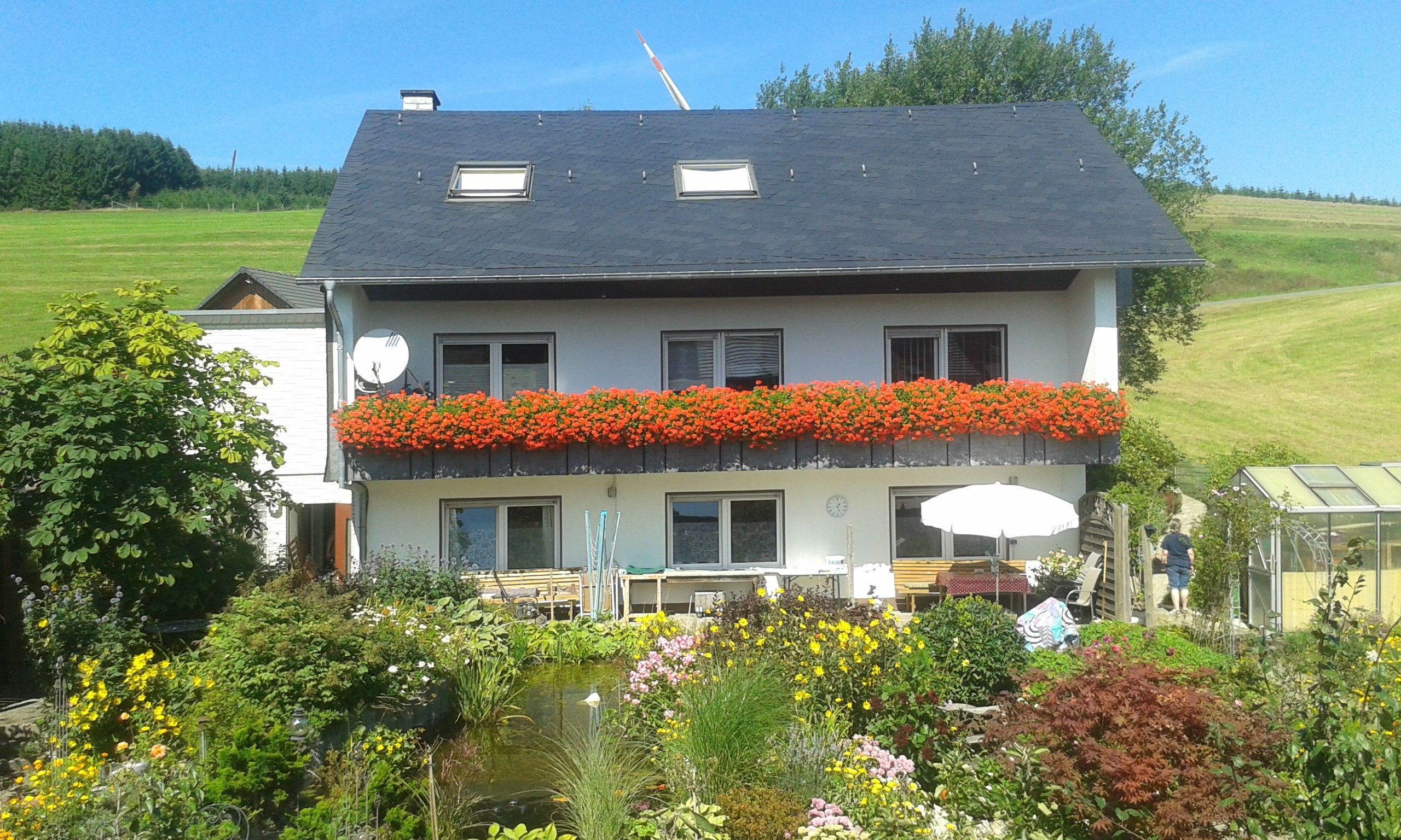 Een tweelaags huis met een balkon, een vijver en een tuin.