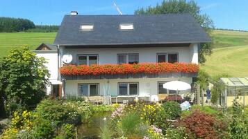 Een tweelaags huis met een balkon, een vijver en een tuin.