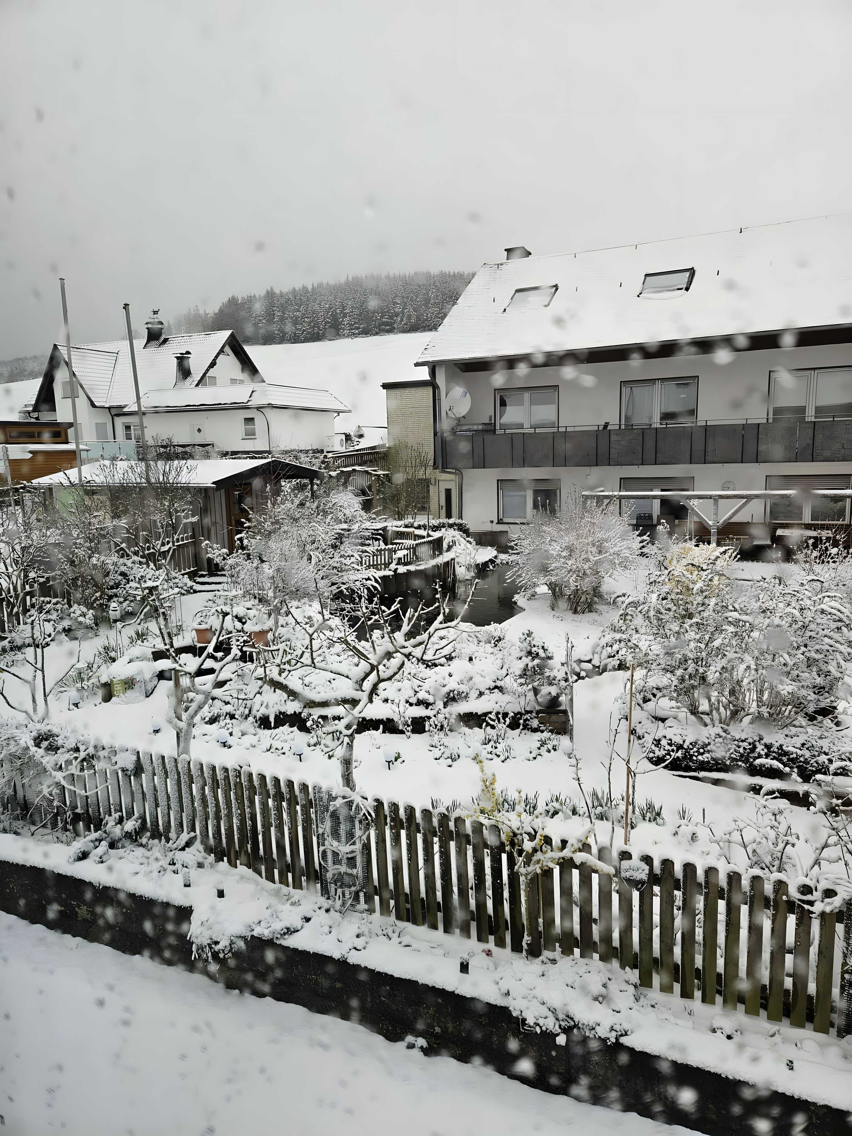Ein Wohngebiet mit schneebedeckten Häusern und einem Holzzaun.