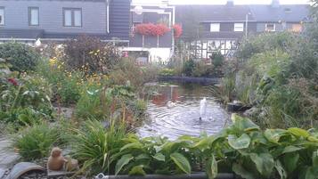 Ein Garten mit Teich, verschiedenen Pflanzen und einem kleinen Springbrunnen.