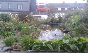 Ein Garten mit Teich, verschiedenen Pflanzen und einem kleinen Springbrunnen.