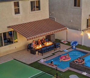 Um quintal com piscina, área de estar externa e cesta de basquete.