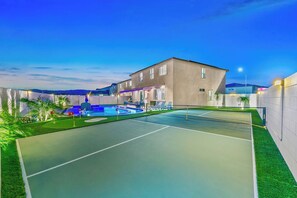 Ein Tennisplatz mit Pool, ein Gebäude mit flachem Dach und ein klarer Himmel.