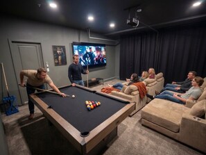 A pool table in a room with a television, sofas, and a door. - The Trilogy: 27 Bedroom/18Bath/Sleeps 60/LazyRiver/Pickleball/GameRoom (Coachella)
