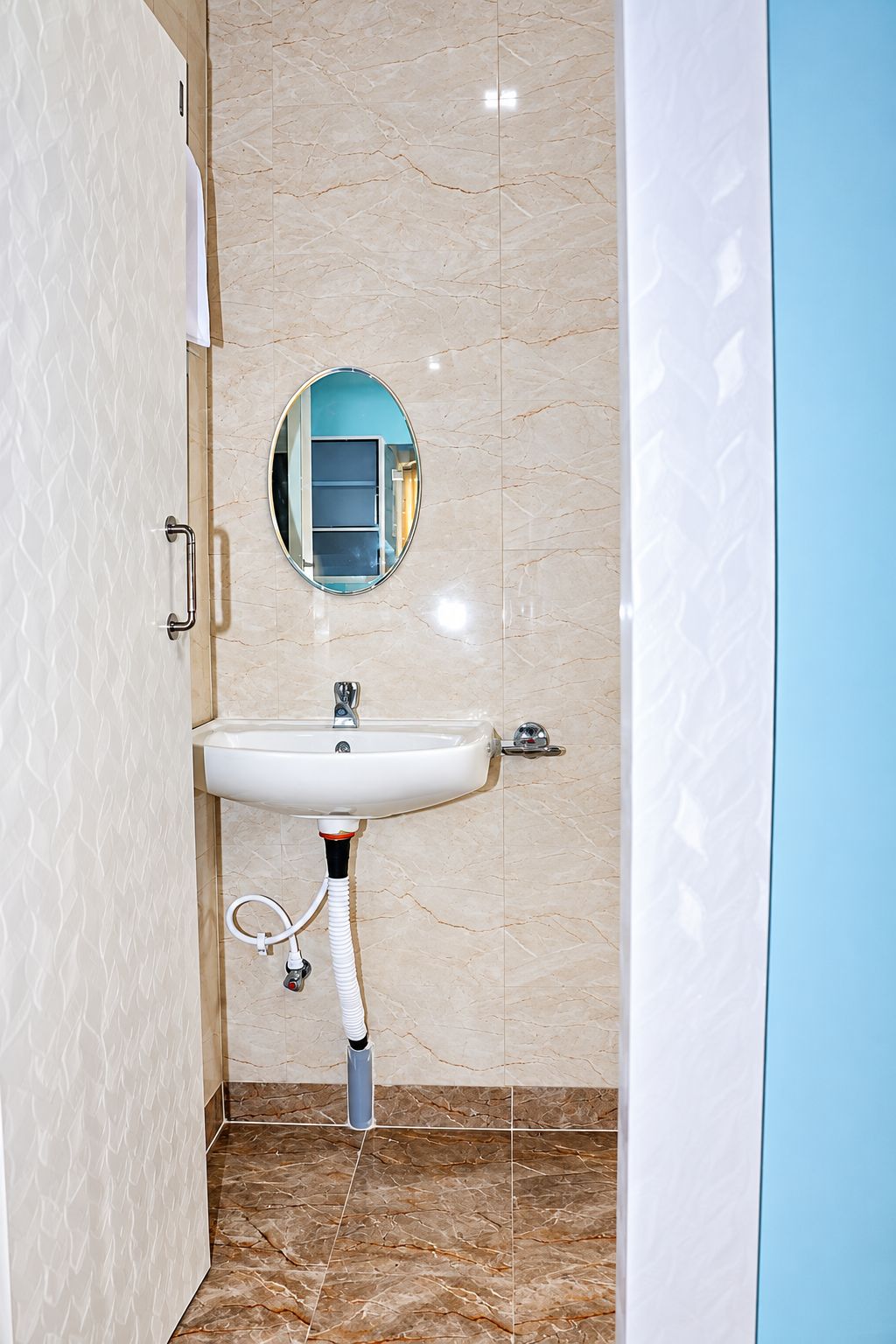 Ein Badezimmer mit einem weißen Waschbecken, einem Spiegel und einem Handtuchhalter.