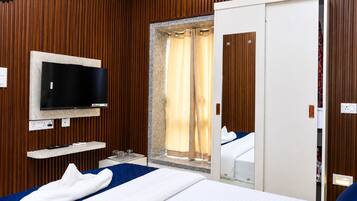 Een hotelkamer met een bed, een aan de muur bevestigde televisie, een badkamer met douchegordijn en houten wandbekleding.