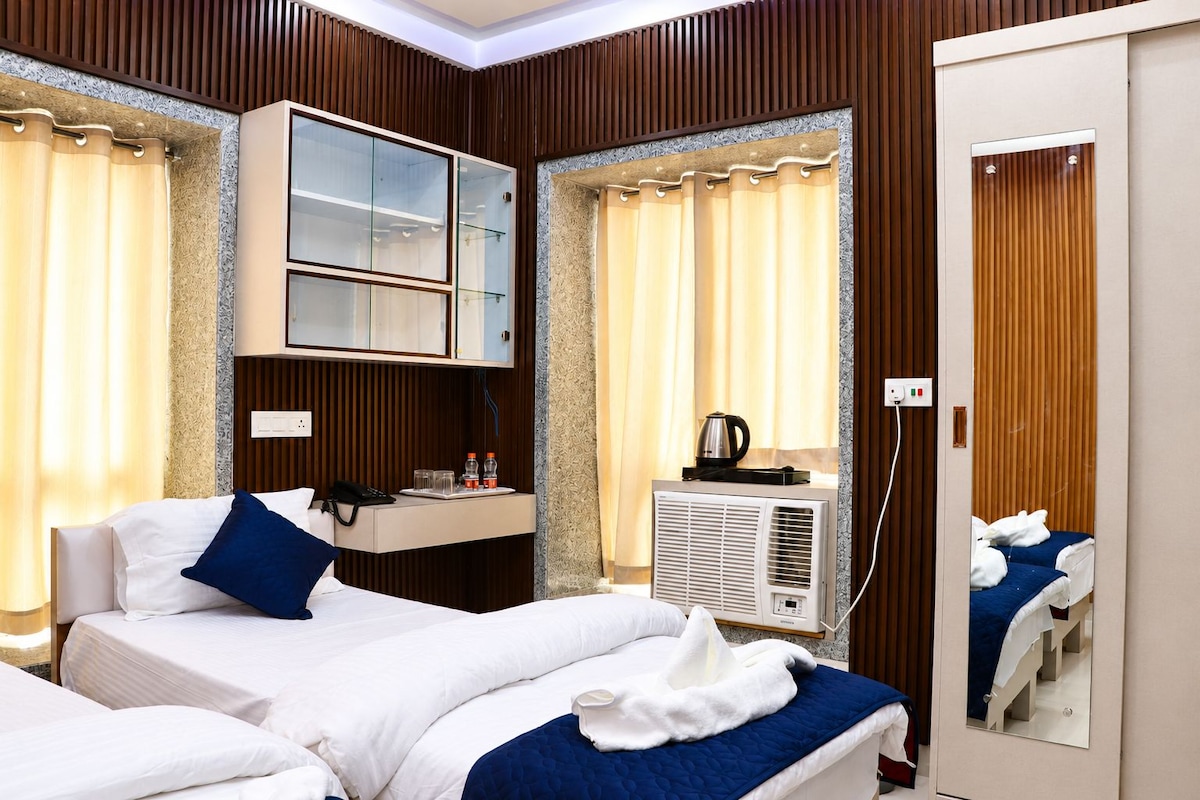 Ein Hotelzimmer mit zwei Betten, einer Minibar, einem Spiegel und einer Klimaanlage.