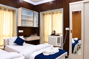 Ein Hotelzimmer mit zwei Betten, einer Minibar, einem Spiegel und einer Klimaanlage.