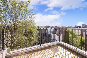 A balcony with a view of a cityscape, metal railing, and a tree. - 2-Bed Chelsea Home with a private Terrace (London)