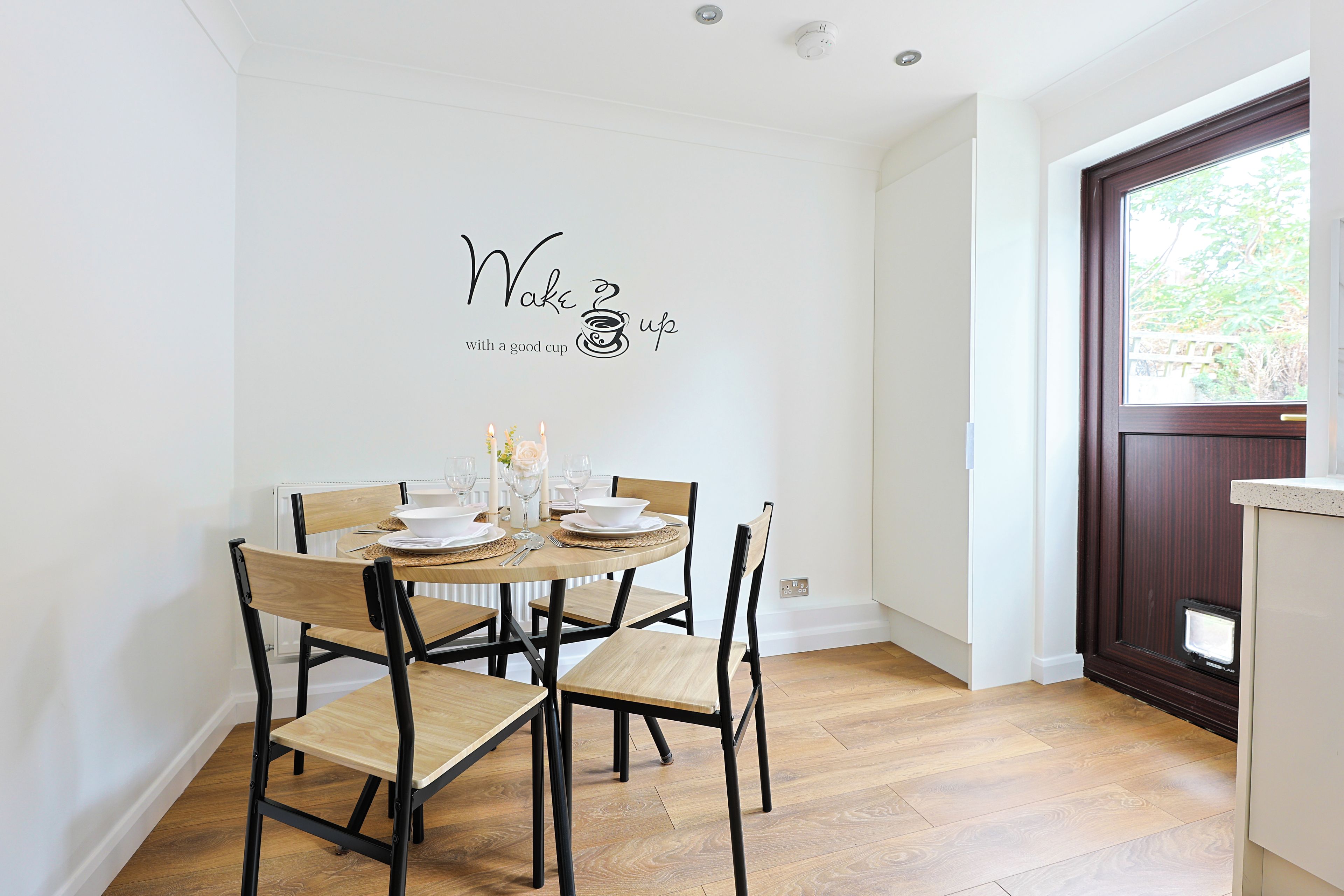 Ein Essbereich mit einem runden Tisch, gedeckt für vier Personen, Stühlen und einem an der Wand befestigten Schild.