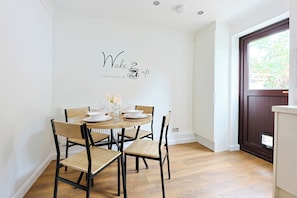 Un comedor con una mesa redonda para cuatro, sillas y un letrero colgado en la pared.