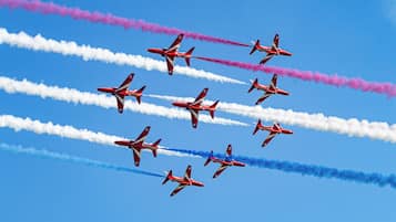 A group of red and white aircraft performing an aerial maneuver with smoke trails.