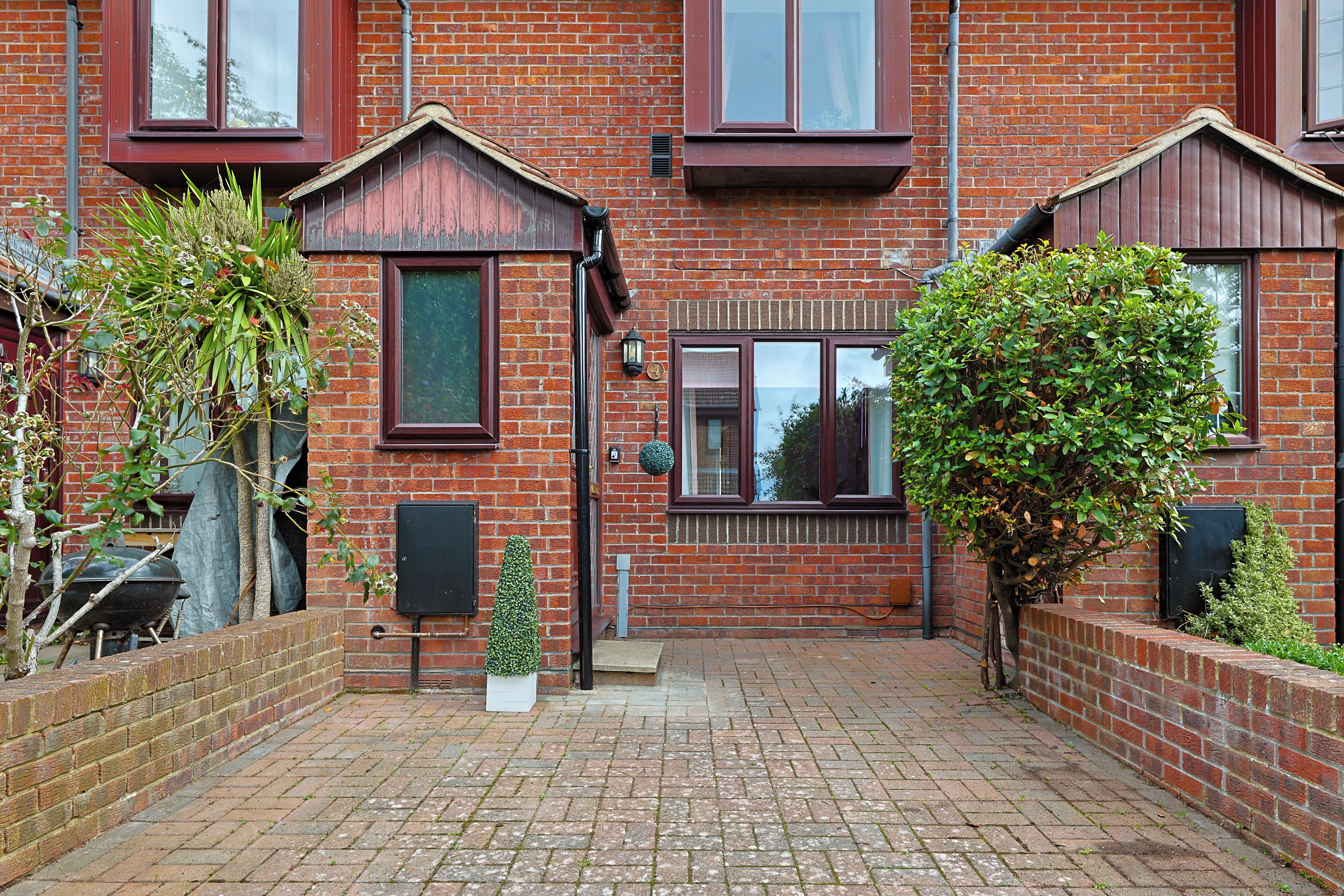 A brick house with a front garden, a mailbox, and a small tree.