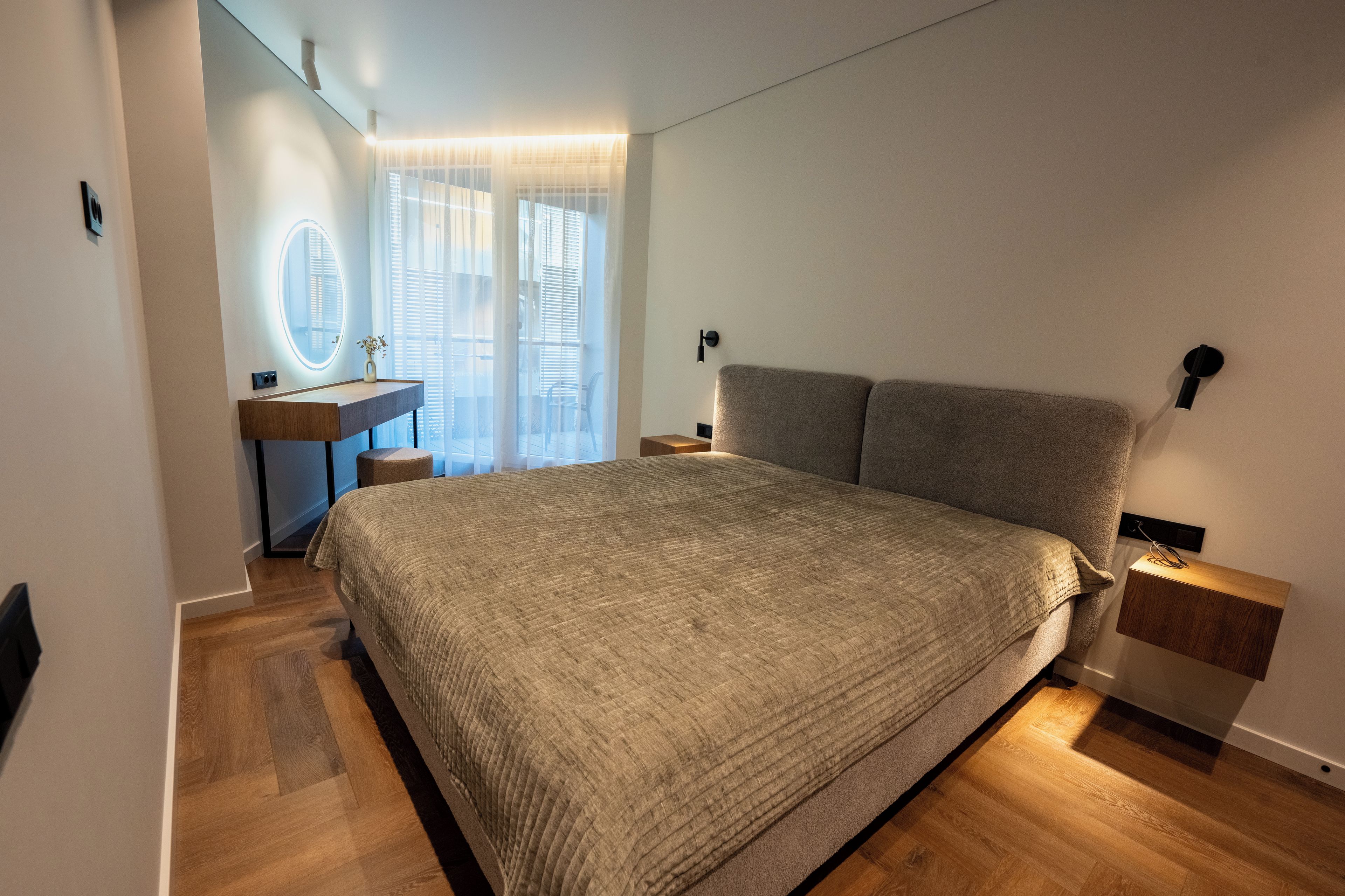 Un dormitorio con una cama grande, una mesita de noche, un espejo y una ventana con persianas.