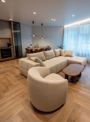 Una sala de estar moderna con un sofá seccional, una mesa de centro de madera y un comedor con una mesa y sillas.