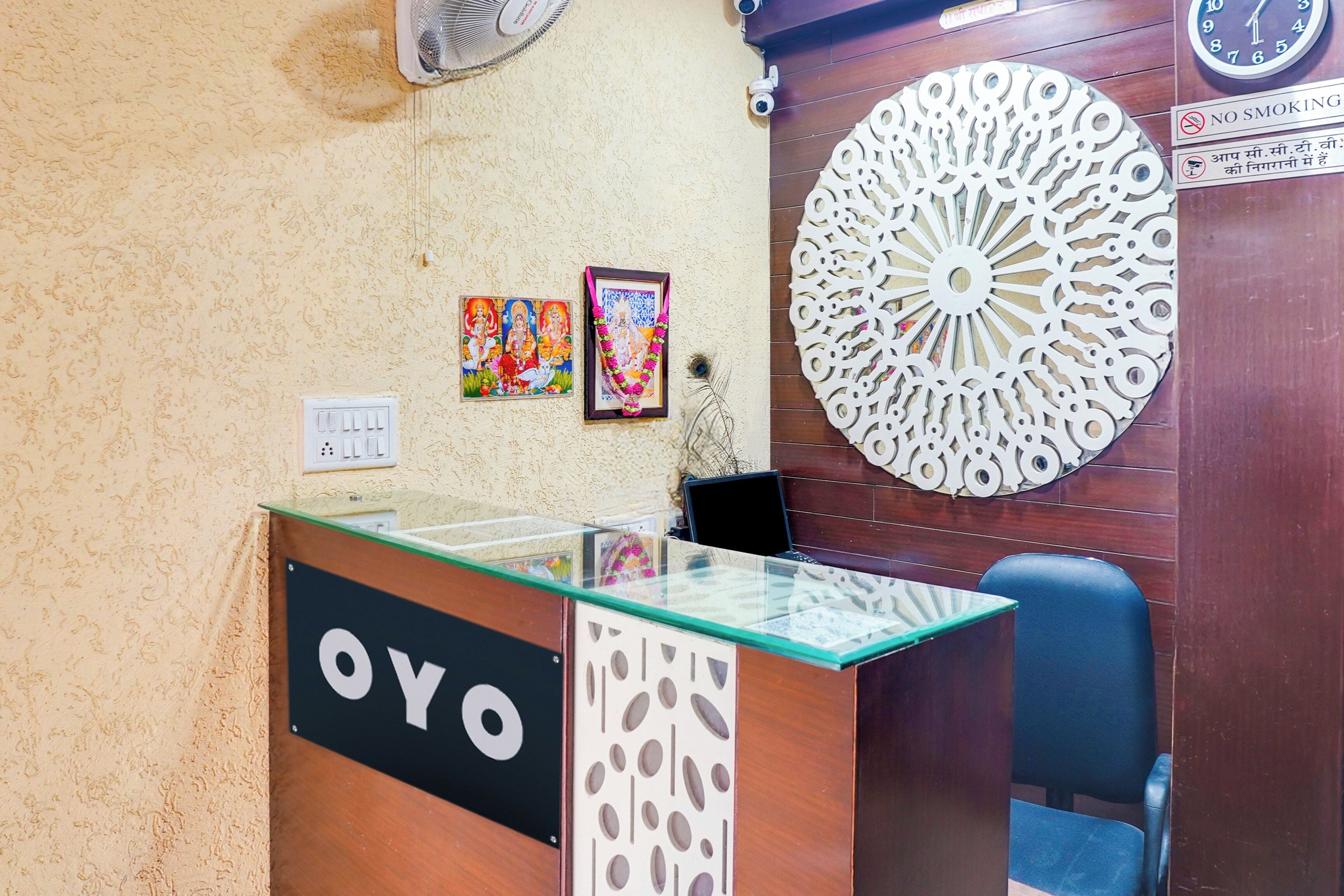 A reception desk with a glass top and a wooden base, a wall clock, and two framed pictures.