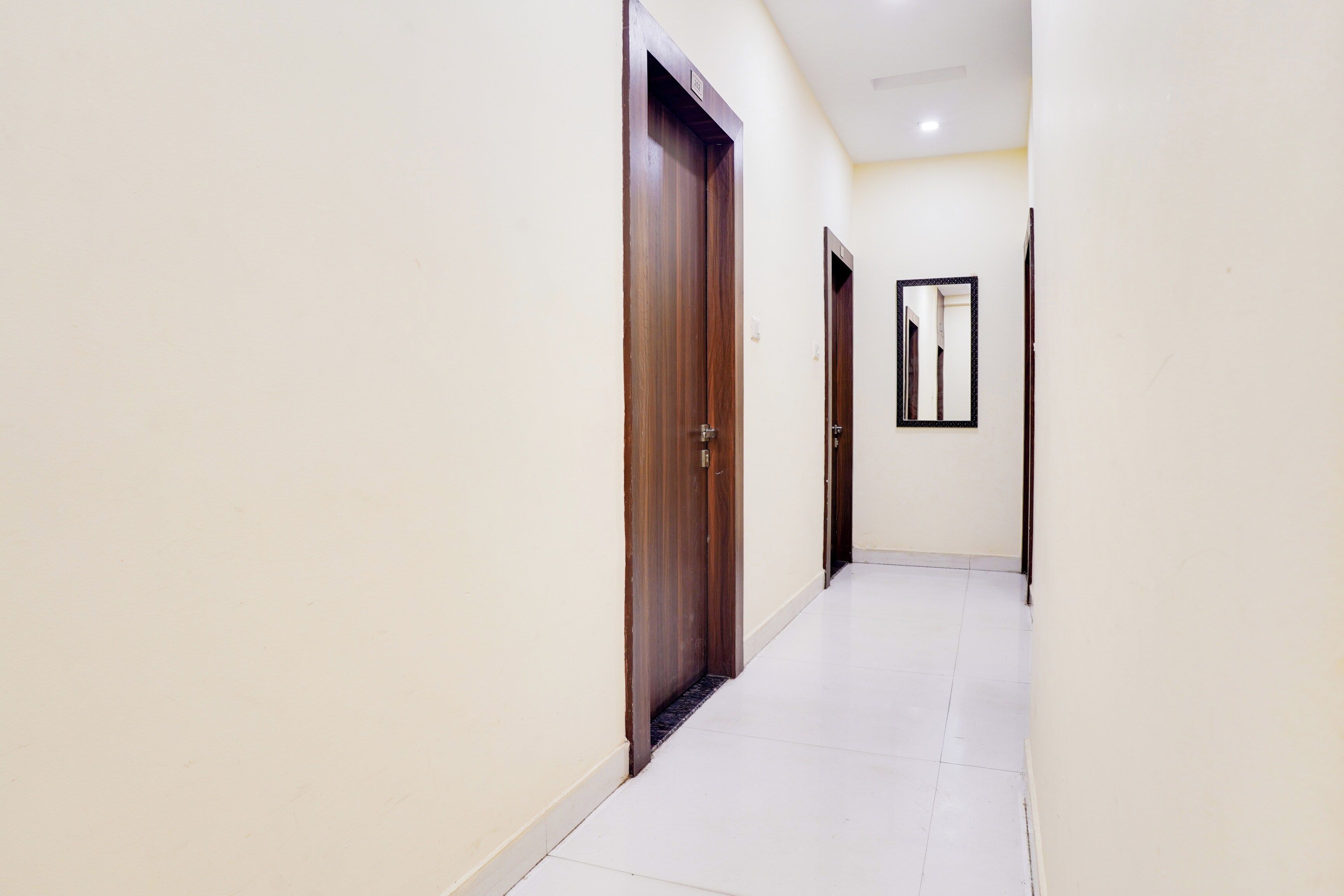 A corridor with wooden doors and a tiled floor.