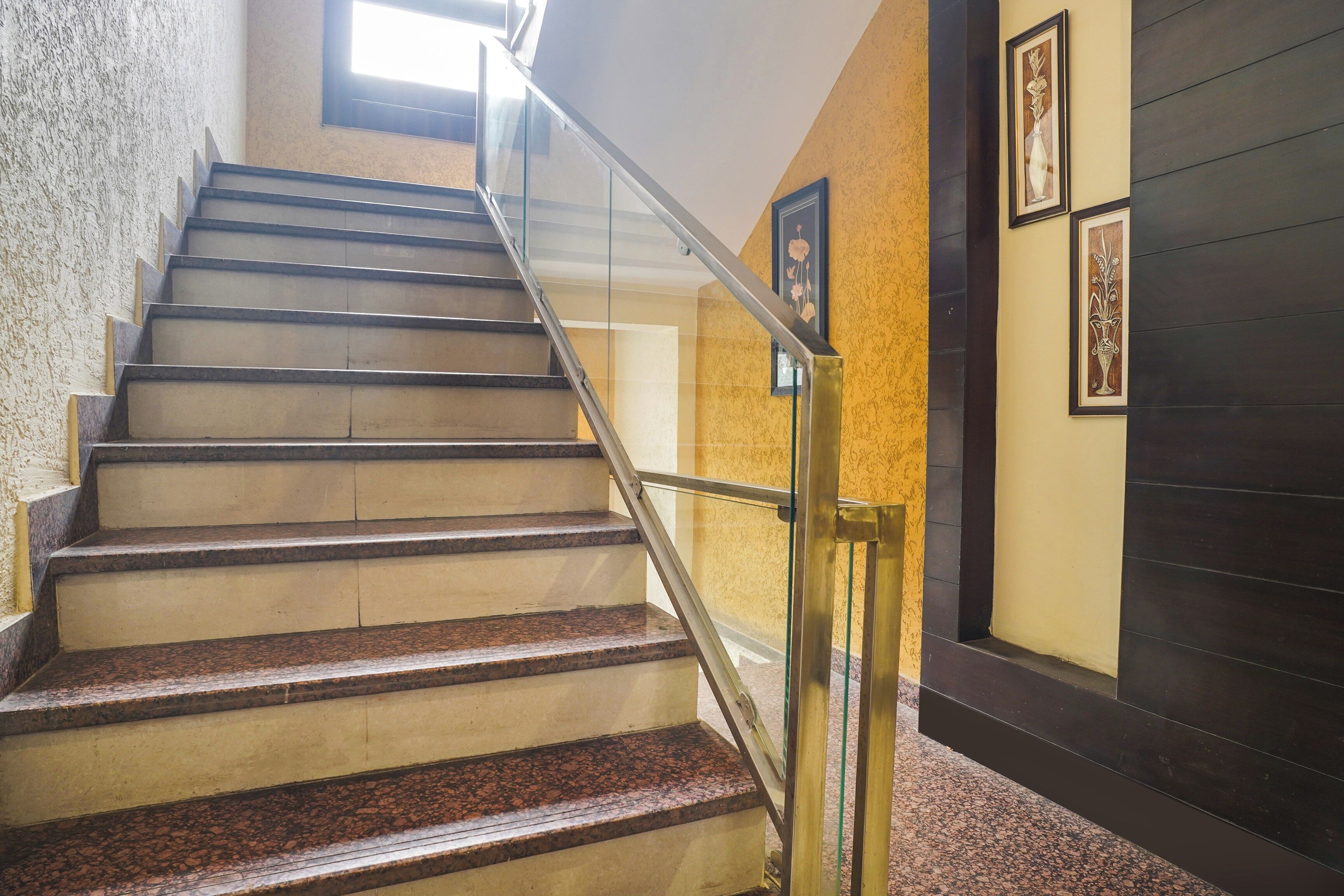 A staircase with a handrail, carpeted steps, and framed artwork on the walls.