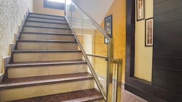 A staircase with a handrail, carpeted steps, and framed artwork on the walls.