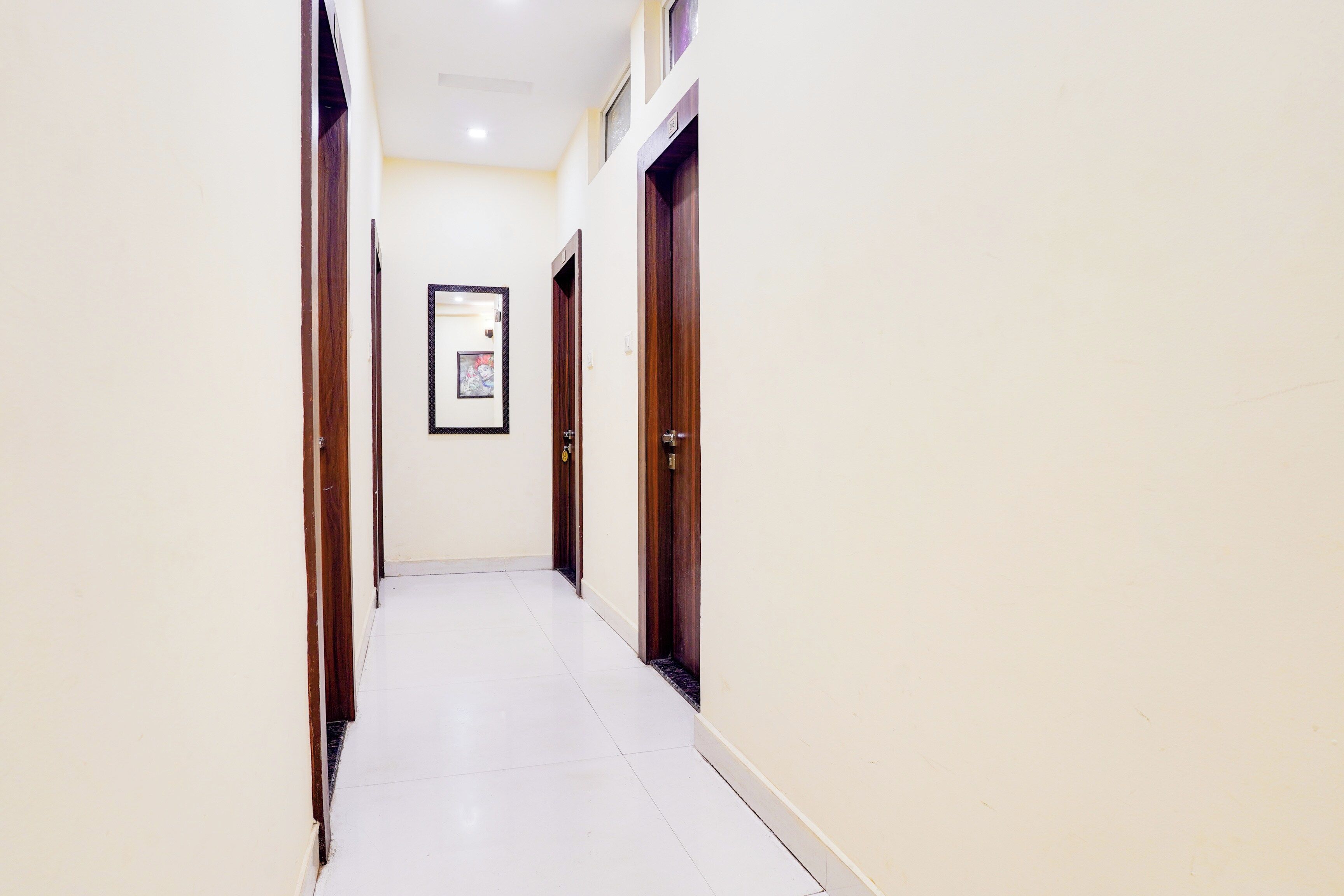 A corridor with doors on both sides, a framed picture on the wall, and a tiled floor.