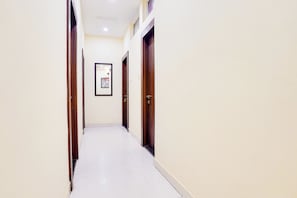 Un pasillo con puertas a ambos lados, un cuadro enmarcado en la pared y suelo de baldosas.