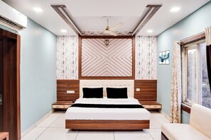 Een slaapkamer met een bed, nachtkastjes, een plafondventilator en een raam met gordijnen.