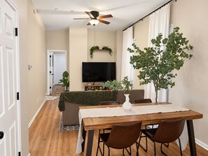 A dining area with a wooden table, brown chairs, a television, and a ceiling fan. - Chic Chicago Retreat, Stylish & Cozy Escape: 3 bedroom (Chicago)