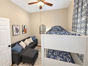 A bedroom with a bunk bed, a sofa, a ceiling fan, and a door. - Chic Chicago Retreat, Stylish & Cozy Escape: 3 bedroom (Chicago)
